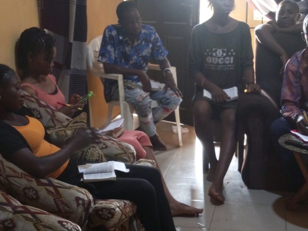 Youths, both male and female, gathered in a Bible study session engaging with Scripture and asking questi